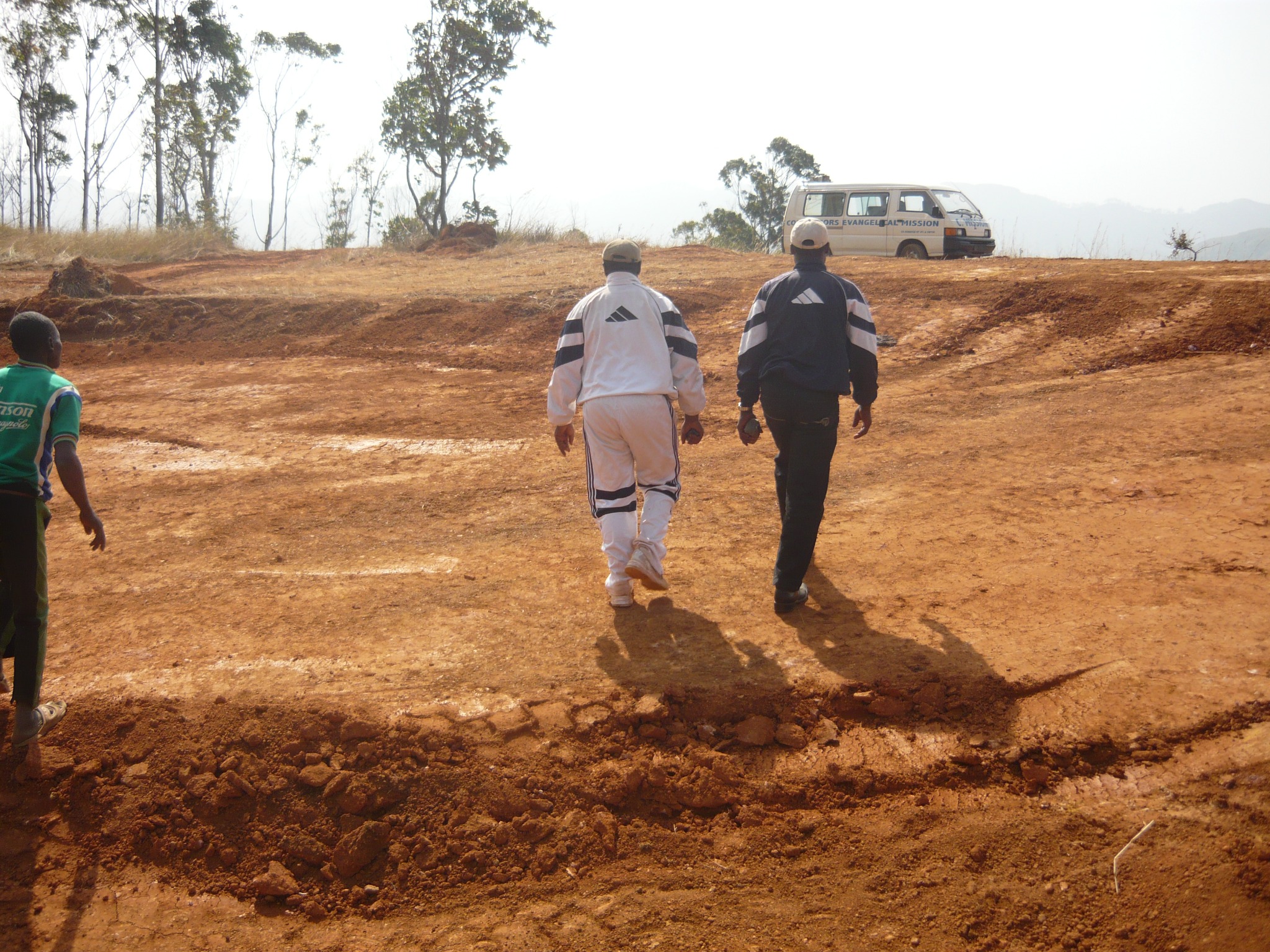 People walking on a dirt road toward a van
